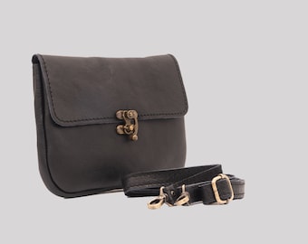 Puede incluir: Un bolso bandolera de cuero negro con cierre de solapa y cierre dorado. El bolso tiene una correa larga ajustable.