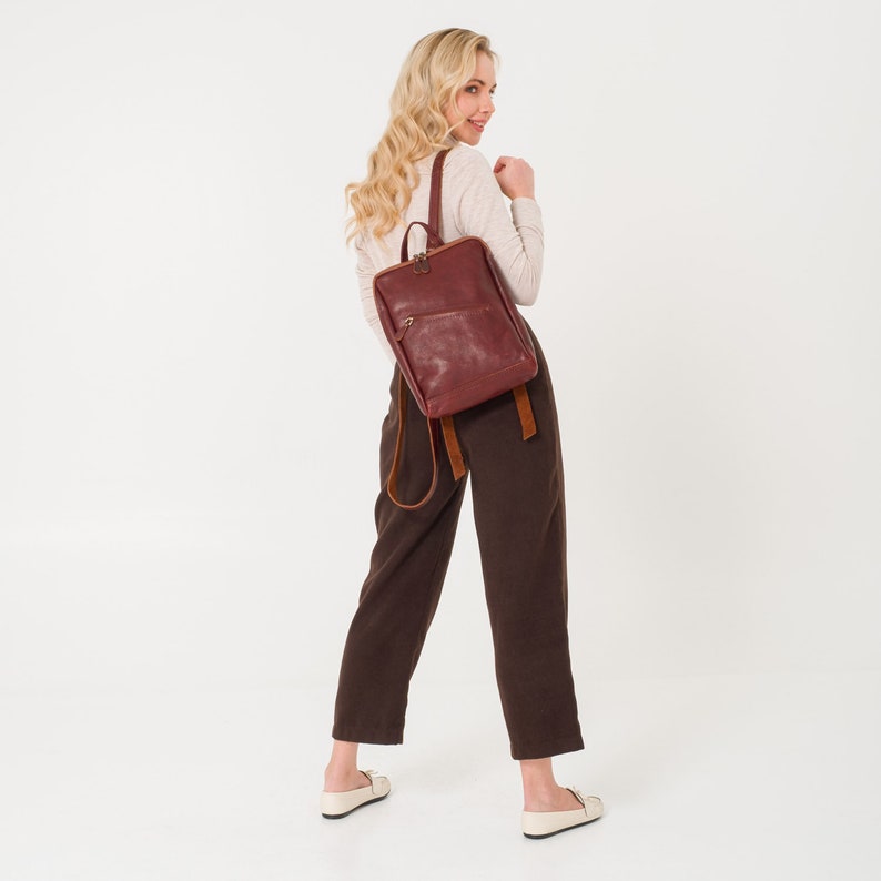May include: A brown leather backpack with a brown leather strap and a zipper closure.