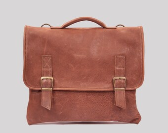 May include: A brown leather briefcase with two buckles on the front and a top handle.