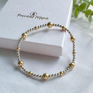 May include: A silver and gold beaded bracelet with a delicate design. The bracelet features alternating silver and gold beads, creating a subtle and elegant look.