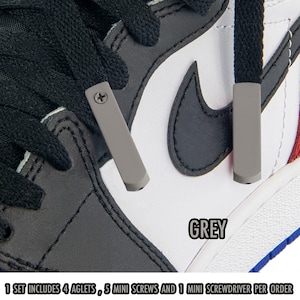 May include: Close-up of a grey aglet with a screw, attached to a black shoelace. The shoe is white, black, and grey with a grey Nike swoosh. The word "GREY" is printed on the image. The text "1 SET INCLUDES 4 AGLETS, 5 MINI SCREWS AND 1 MINI SCREWDRIVER PER ORDER" is also printed.