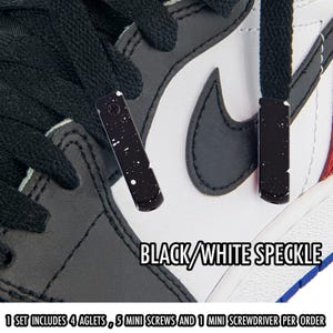 May include: Close-up of a black and white sneaker with black aglets. The aglets have a black speckled design. The text "BLACK/WHITE SPECKLE" is visible. The text "1 SET INCLUDES 4 AGLETS, 5 MINI SCREWS AND 1 MINI SCREWDRIVER PER ORDER" is also visible.