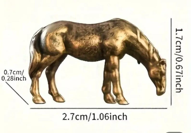 Puede incluir: Figura de camello de color bronce, de 2,7 cm de largo, 1,7 cm de alto y 0,7 cm de ancho. El camello est&aacute; representado en una pose de pastoreo, con la cabeza baja. La figura tiene una textura detallada y probablemente es de metal.