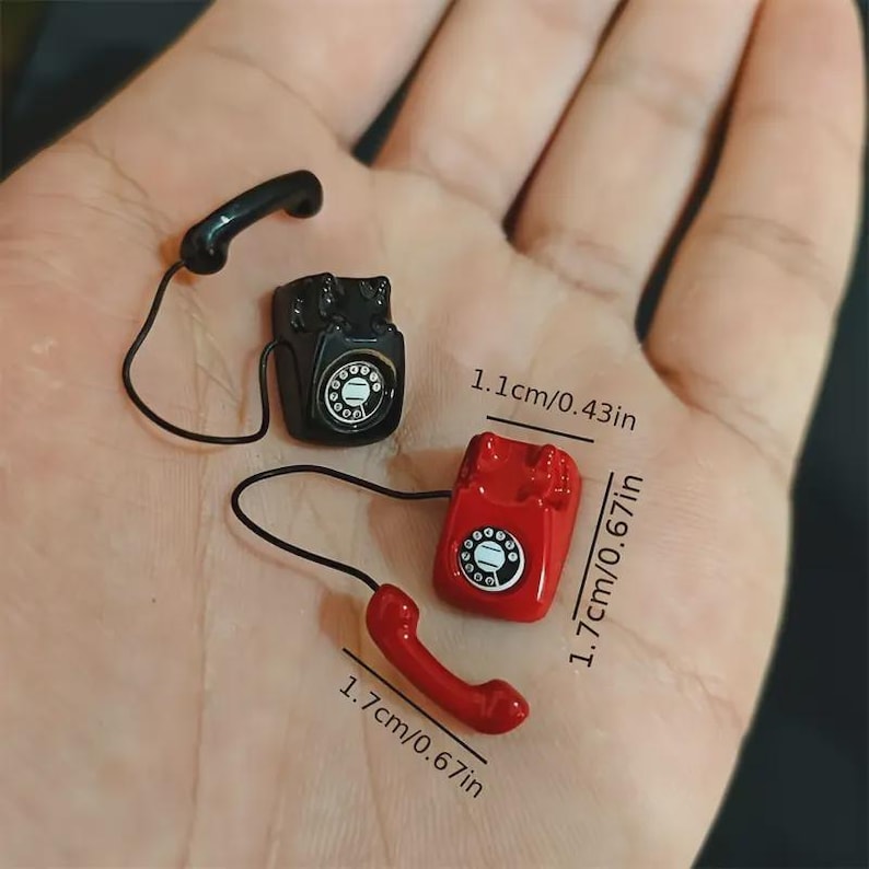 Puede incluir: Miniaturas de tel&eacute;fonos de estilo vintage en negro y rojo. El tel&eacute;fono rojo mide 1,7 cm de alto y el tel&eacute;fono negro mide 1,1 cm de alto. Cada tel&eacute;fono tiene un auricular y un dial. Los tel&eacute;fonos son peque&ntilde;os y detallados.
