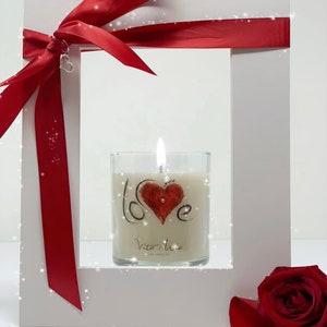 White frame with a red ribbon. In the center of the frame is the Vita Mia love candle adorned with Swarovski crystals.