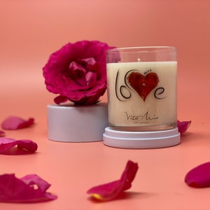 Love candle: love spelled out on glass tumbler. To the left, a ceramic lid with a flower on top of the lid.