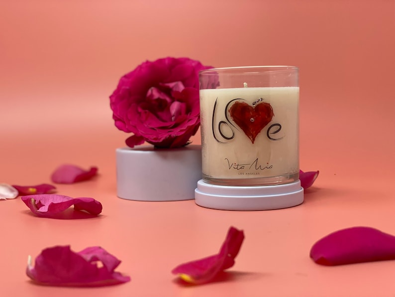 Love candle: love spelled out on glass tumbler. To the left, a ceramic lid with a flower on top of the lid.