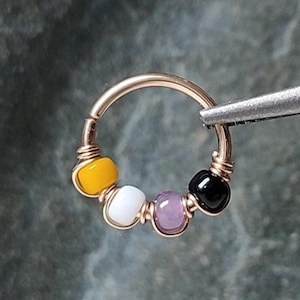 以下が含まれることがあります： 黄色、白、紫、黒のビーズが付いたゴールドのフープピアス