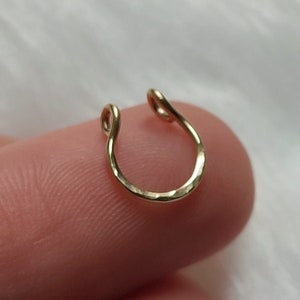 A dainty gold filled fake septum ring, with a shimmery, lightly hammered texture that reflects the light beautifully