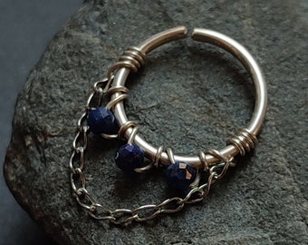 May include: Silver hoop earring with a dangling chain and three blue gemstone beads.