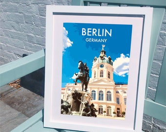 May include: A white framed print with a blue sky and a white building with a statue in front of it. The print says "BERLIN GERMANY" at the top.