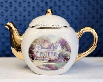 Tetera de cerámica coleccionable con detalles dorados "El hogar está donde está el corazón" de Thomas Kinkade.