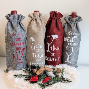 Könnte beinhalten: Vier Weinflaschenbeutel in Grau, Beige und Rot mit weißem Text und Grafiken. Die Beutel haben einen Kordelzugverschluss und sind mit Sätzen wie "Frohliche Wein Nachten" und "Gluhwein ist wie Tee" verziert.