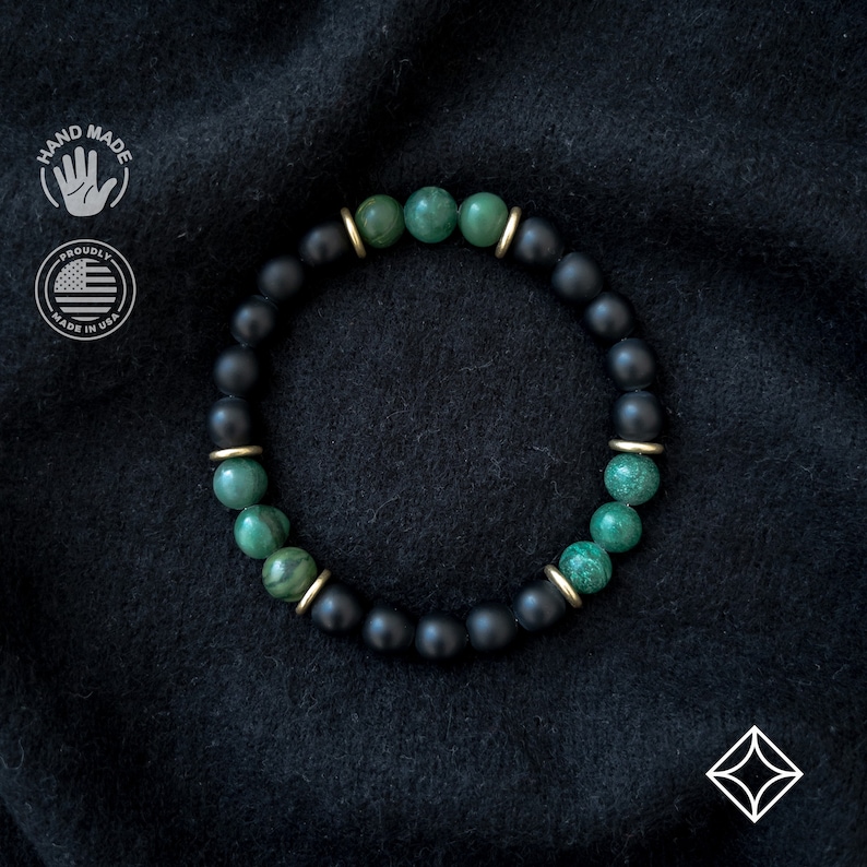 May include: A black and green beaded bracelet with gold accents. The bracelet is made with black onyx and green jade beads.