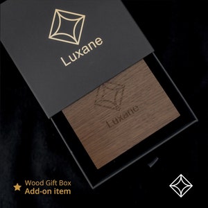 May include: A black gift box with a gold geometric logo that says "Luxane" on the top. The box is open and reveals a wooden box with the same logo engraved on the top. The text "Wood Gift Box Add-on item" is written below the image.