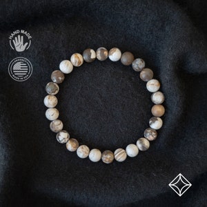 Puede incluir: Un brazalete de piedra de ágata blanca y marrón con una etiqueta de "hecho a mano". El brazalete está hecho en los Estados Unidos.