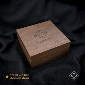 May include: A wooden gift box with a geometric design and the word "Luxane" engraved on the top. The box is made of dark brown wood and has a natural finish.