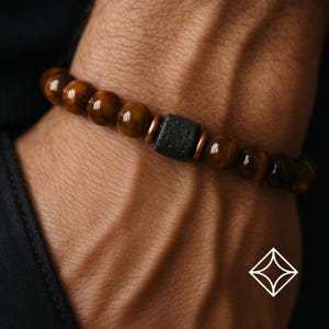 May include: A brown tiger's eye beaded bracelet with a black lava rock bead and copper spacers.