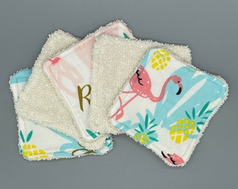 May include: Set of five reusable makeup remover pads. Two pads are white terry cloth and three pads are printed with pink flamingos and yellow pineapples on a blue background.