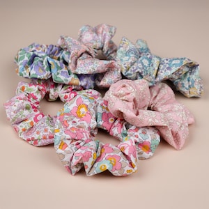 Peut inclure: Plusieurs chouchous à motifs floraux de différentes couleurs. Les chouchous présentent divers motifs floraux dans des tons de rose, de bleu, de violet et de blanc. Les chouchous sont en tissu et sont conçus pour attacher les cheveux.