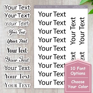 May include: A sheet of white stickers with the text "Your Text" in various fonts. A pink sign indicates 10 font options and color choices. The stickers are on a light wood surface.