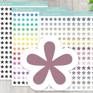May include: Three sheets of stickers with a variety of colored starburst shapes. The stickers are arranged in rows and columns. The sheets are labeled with the text "The Journal Effect" and a website address. A large, pink, five-pointed starburst shape is in the foreground.