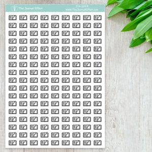 May include: A sheet of 100 black and white planner stickers featuring an open book with a pencil icon. The stickers are designed for use in a planner or journal.