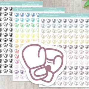 May include: A sheet of stickers with a variety of boxing glove designs. The stickers are in different colors, including black, white, red, blue, green, yellow, and purple. The stickers are arranged in rows and columns on a white background. The text "The Journal Effect" and "ICN-122-B" is printed on the sheet.