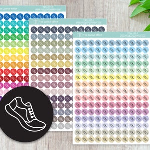 May include: Three sheets of colorful stickers with a running shoe design. Each sheet has a different color gradient, with the first sheet being blue to green, the second sheet being gray to brown, and the third sheet being light blue to beige. The sheets are labeled with the text "The Journal Effect" and a website address.