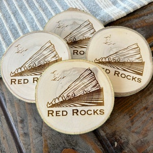 May include: Four wooden coasters with a brown, engraved image of a mountain range and the text "Red Rocks".