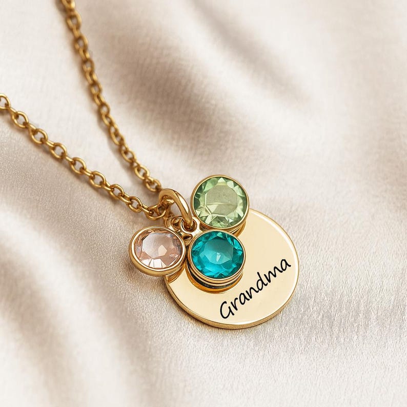 A gold necklace with a gold round charm and three small gem charms