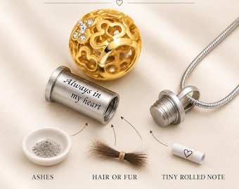 May include: A gold-toned spherical pendant with cut-out patterns and crystal accents, paired with a silver-toned cylindrical cremation urn necklace engraved with "Always in my heart." The set includes a small white dish of ashes, a lock of hair, and a tiny rolled note with a heart icon.