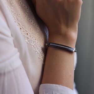A silver stainless steel bracelet with a Cuban link chain and a curved bar adorned with sparkling crystals. The elegant and sophisticated design makes it a perfect accessory for both casual and formal wear, adding a touch of brilliance to any outfit.
