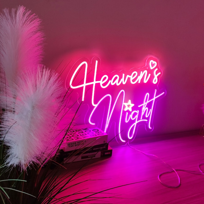 Puede incluir: Letrero de ne&oacute;n rosa con el texto "Heaven's Night" con un peque&ntilde;o gr&aacute;fico de estrella y coraz&oacute;n.