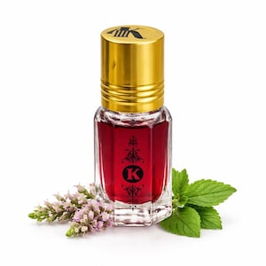 May include: A small, clear glass perfume bottle filled with a deep red liquid, topped with a gold cap. The bottle has a black 'K' and decorative elements. Fresh mint and lavender sprigs are arranged around the bottle.