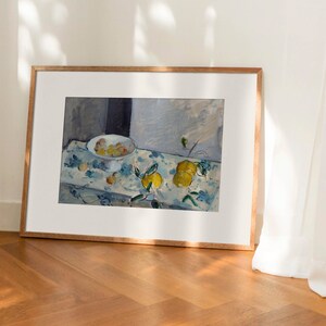 May include: A framed painting of a still life with a bowl of fruit and lemons on a table with a blue and white patterned tablecloth.