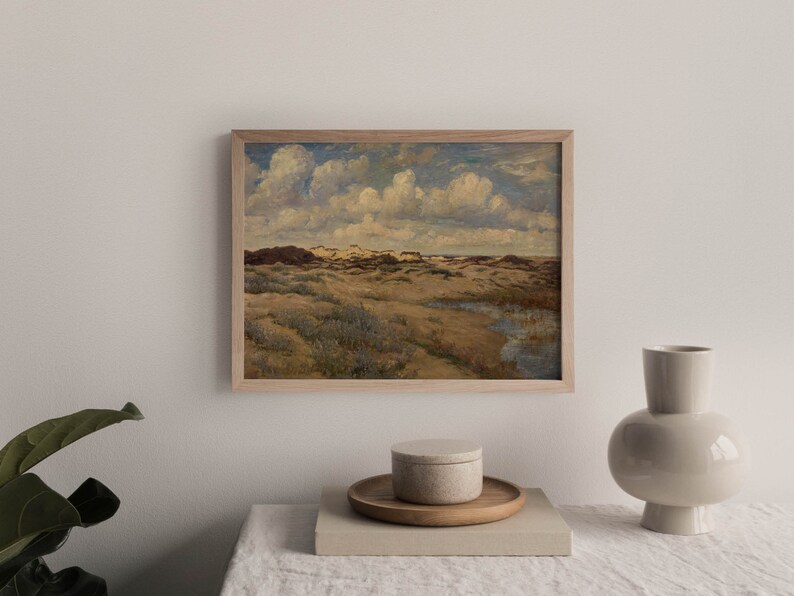 May include: A framed painting depicting a landscape with rolling hills, green grass, and a cloudy sky. The painting is in a wooden frame and is hanging on a white wall.