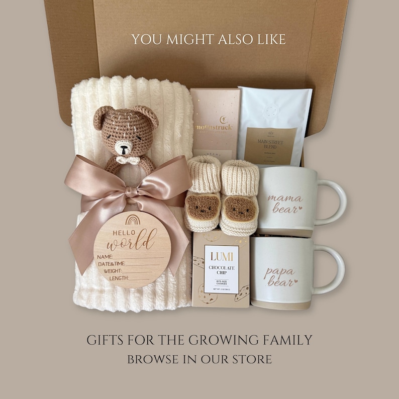 Puede incluir: Una caja de regalo que contiene una manta acanalada color crema con un sonajero de oso tejido a crochet marr&oacute;n, un disco de madera 'Hello World' para nacimiento, patucos color crema con caras de oso, dos tazas 'mama bear' y 'papa bear', caf&eacute; y chocolate.