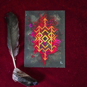 May include: A dark gray artwork with a geometric design in yellow and red, accented with pink splashes. A black feather and a crystal are positioned to the left on a red velvet surface. The artwork features a central diamond shape.