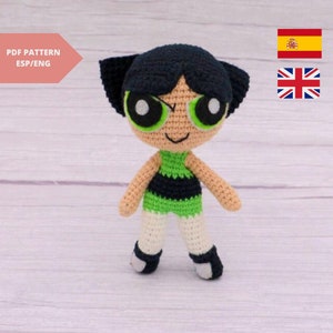 May include: Crocheted plush toy of a cartoon character with black hair, green eyes, and a green and black outfit. The toy is standing on a light wood surface.  PDF PATTERN ESP/ENG