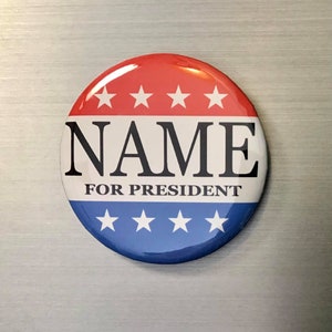 May include: A round campaign button with a red top section featuring four white stars, a white center with the word "NAME" in bold black letters, and the words "FOR PRESIDENT" below. The bottom section is blue with four white stars.