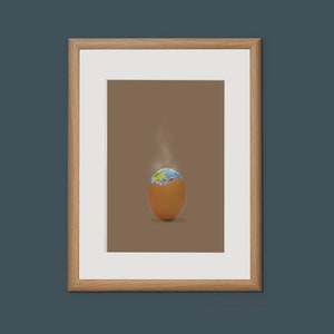 May include: A framed print depicting a brown egg with a cracked shell revealing a miniature Earth inside. Steam rises from the egg, suggesting a hatching process.