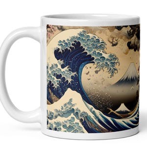 Può includere: Tazza in ceramica bianca con un design di stampa xilografica giapponese. L'opera raffigura una grande onda oceanica con il Monte Fuji sullo sfondo, nei toni del blu, bianco e beige. Il design presenta dettagli intricati.