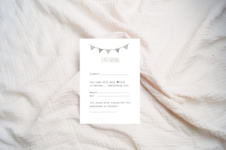 May include: A white card with black text and a simple illustration of a string of flags. The text reads "EINLADUNG" and includes the phrase "Ich lade Dich ganz herzlich zu meinem Geburtstag ein."  The card also has blank lines for the date, time, and location of the event.