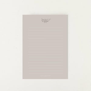 Könnte beinhalten: Ein hellgrauer, linierter Notizblock mit einer einfachen schwarzen Linienzeichnung eines Zweigs mit Blättern oben. Der Text "notes you'll cherish" ist unten auf der Seite gedruckt.
