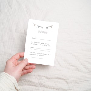 May include: A white card with black text that reads "Einladung" (Invitation) with a string of gray and white triangle flags at the top. The text on the card reads: "Liebe/r, Ich lade Dich ganz herzlich zu meinem Geburtstag ein. Wann?  Wo? Ich freue mich riesig mit Dir gemeinsam zu feiern!"