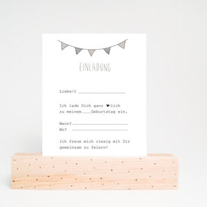 May include: A printable birthday invitation card with a string of flags at the top and the text "EINLADUNG" in black. The text reads "Liebe/r, Ich lade Dich ganz herzlich zu meinem. Geburtstag ein. Wann? Wo? Ich freue mich riesig mit Dir gemeinsam zu feiern!"