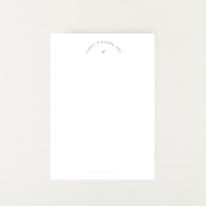 Könnte beinhalten: Eine weiße Karte mit dem Text "today is a good day" in hellgrauer Schrift, ergänzt durch ein kleines graues Herz. Das Design ist minimalistisch und für verschiedene Anlässe geeignet. Schlicht und elegant.