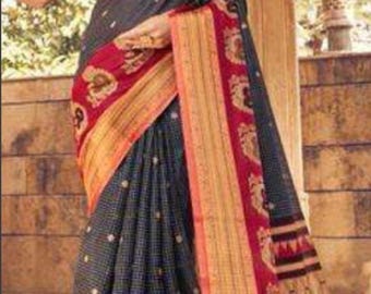 May include: A woman wearing a dark blue and red saree with gold accents. The saree has a checkered pattern and a floral design. The saree is draped over her shoulders and around her waist. The woman is standing in front of a wooden wall. The number 728 is visible in the bottom right corner of the image.