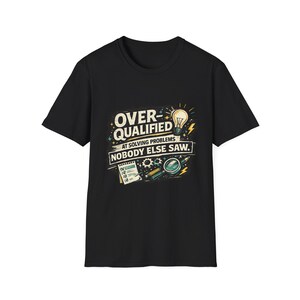 Könnte beinhalten: Ein schwarzes Kurzarm-T-Shirt mit einem Grafikdruck und dem Text OVER-QUALIFIED AT SOLVING PROBLEMS NOBODY ELSE SAW. Das Design zeigt eine Glühbirne, eine Checkliste, Zahnräder und eine Lupe in den Farben Gelb, Blau und Weiß.